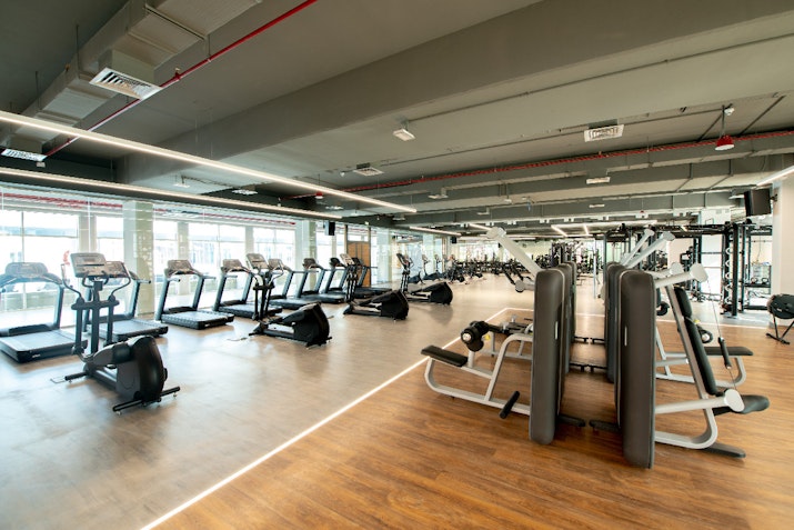 Spacious gym with cardio machines, weight training equipment, and large windows for natural light