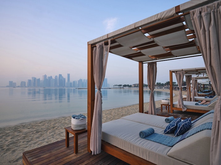 Beach cabanas with towels overlooking a city skyline at sunrise