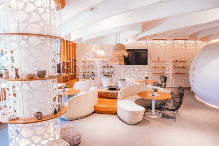 Stylish and modern interior of a lounge with curved white walls, cozy seating, and decorative shelves