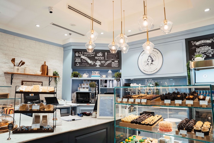 Cozy bakery interior with a display of various pastries, a counter, and pendant lighting.