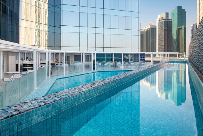 Rooftop pool with glass walls, reflecting the city skyline