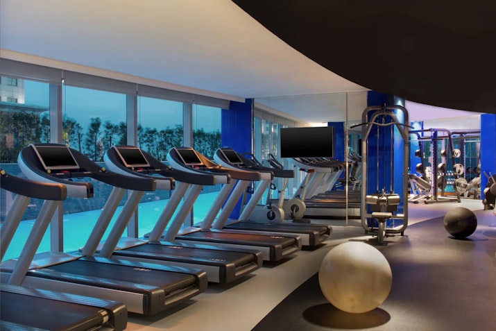 Modern gym with treadmills, exercise equipment, and large windows.
