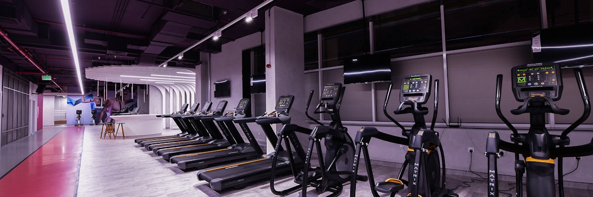 M Active Ladies Modern gym with cardio equipment, including treadmills and ellipticals, under sleek lighting.