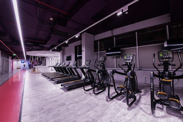 Modern gym with cardio equipment, including treadmills and ellipticals, under sleek lighting.