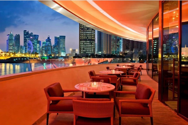 Outdoor restaurant seating with a stunning view of the city skyline and illuminated buildings at night