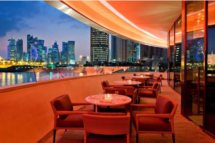 Outdoor restaurant seating with a stunning view of the city skyline and illuminated buildings at night