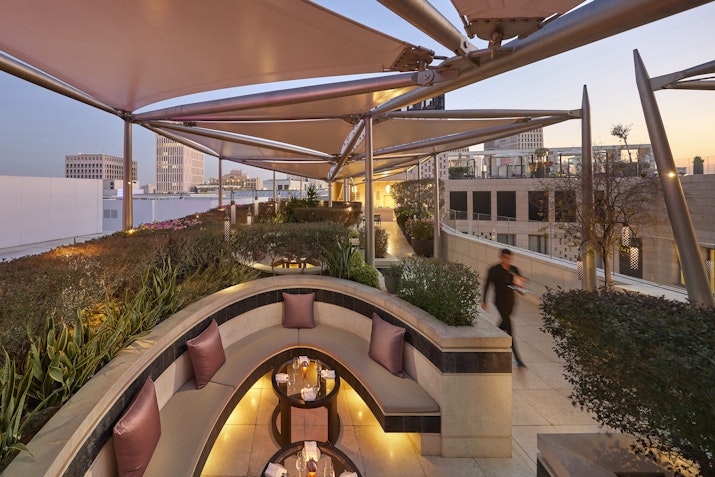 Aqua at Mandarin Oriental Doha Modern rooftop terrace with seating area and city view at dusk.