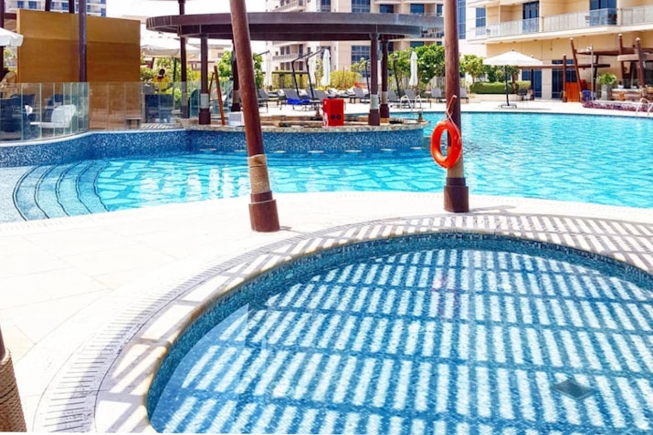 Swimming pool with shaded areas and a lifebuoy ring on the side.