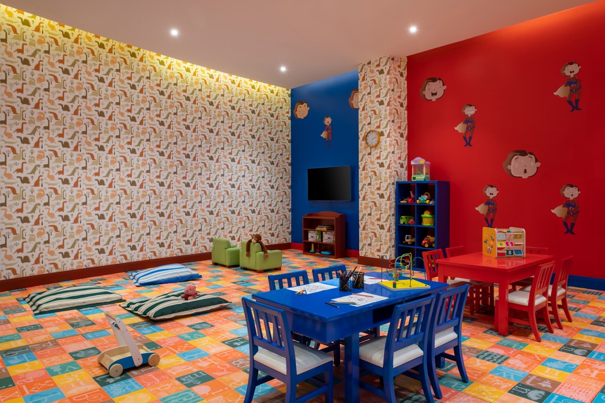 Brightly colored children's playroom with themed walls, toy storage, and blue and red furniture.