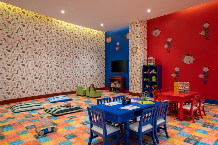 Brightly colored children's playroom with themed walls, toy storage, and blue and red furniture.