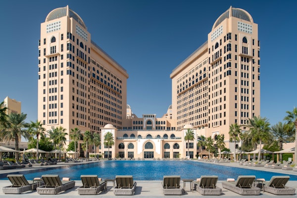 Luxurious resort with two towers and a large outdoor swimming pool surrounded by lounge chairs.