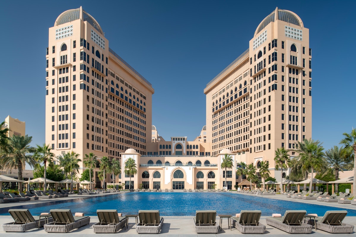 Luxurious resort with two towers and a large outdoor swimming pool surrounded by lounge chairs.