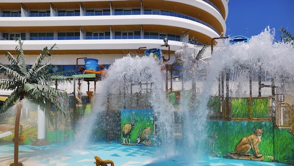 Water play area with large water features, colorful animal-themed murals, and a hotel building in the background.