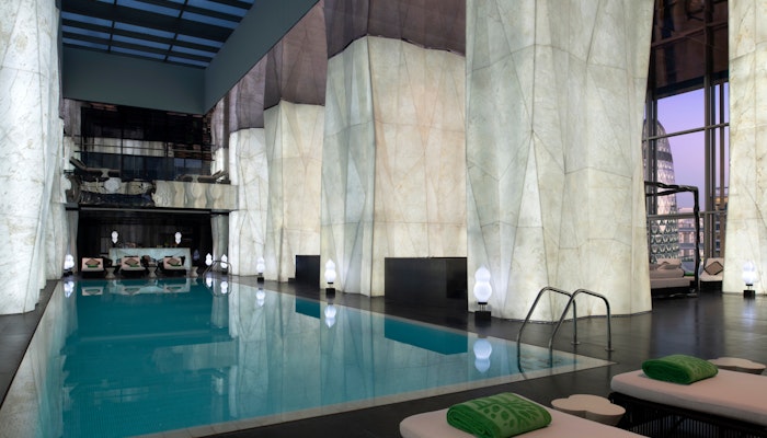 Banyan Tree Doha Indoor swimming pool with marble walls, lounge chairs, and modern lighting.