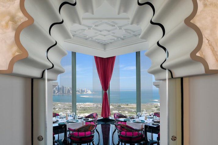 Elegant dining room with panoramic ocean views, framed by ornate architecture and rich red curtains