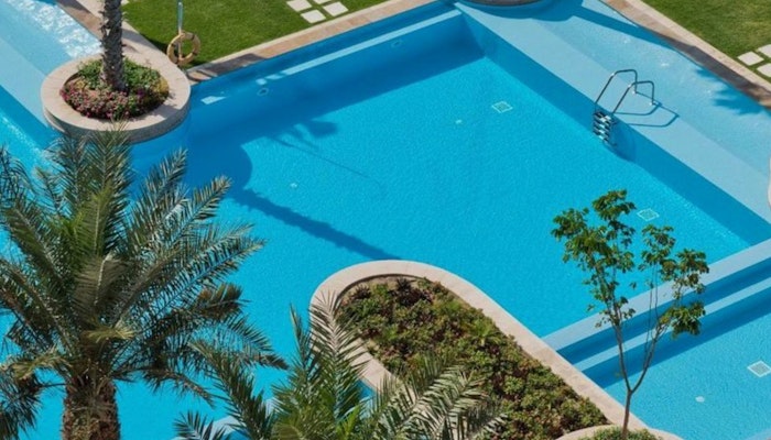 Marsa Malaz Kempinski, The Pearl Swimming pool surrounded by palm trees and landscaped garden.