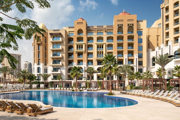 Resort building with a large outdoor swimming pool and lounge chairs.