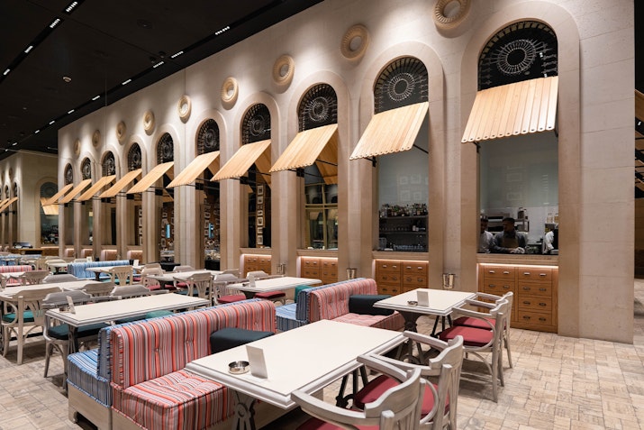 Stylish restaurant interior with rows of tables and large arched windows