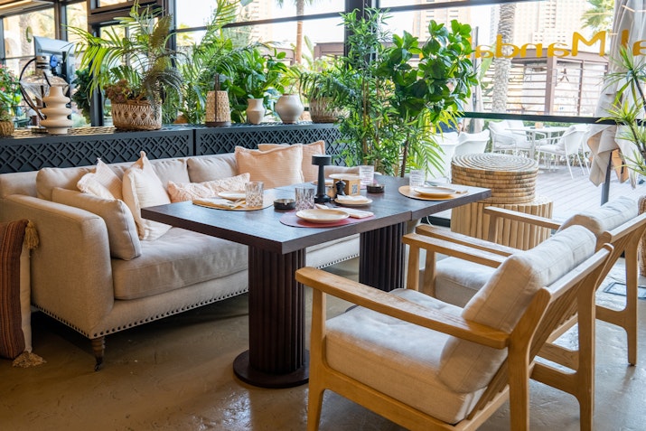 Cozy café seating area with a table set for dining and lush greenery.