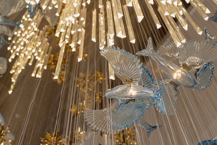 Artistic chandelier with glass birds and golden light strands.