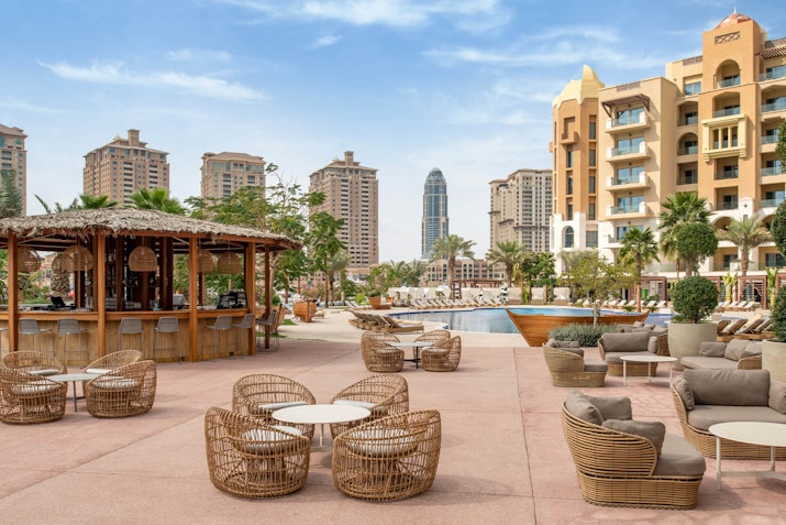 Outdoor seating area with wicker furniture, a bar, and a view of the city skyline