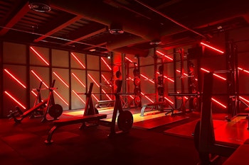 Gym with intense red lighting, highlighting the workout equipment and creating an energizing atmosphere.