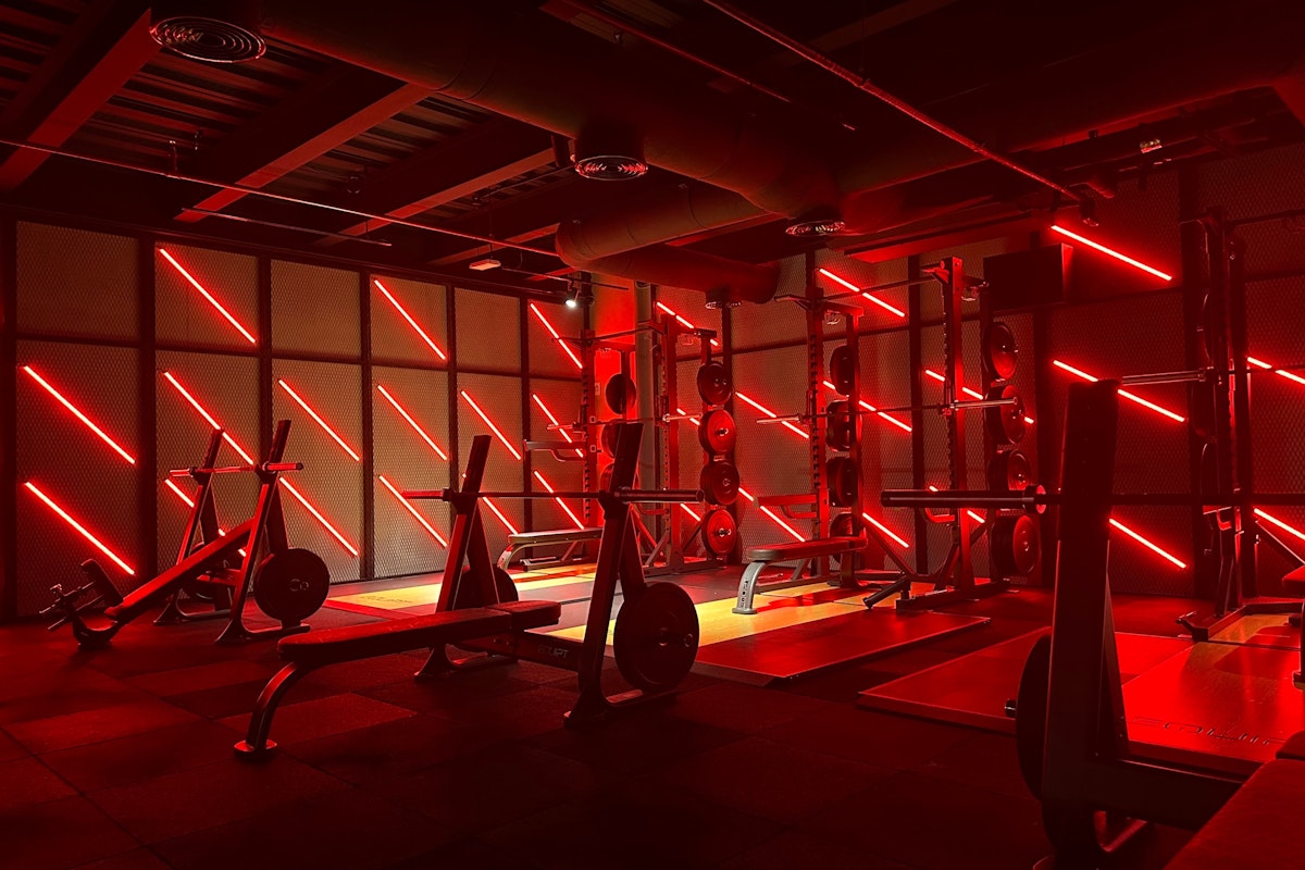 Gym with intense red lighting, highlighting the workout equipment and creating an energizing atmosphere.