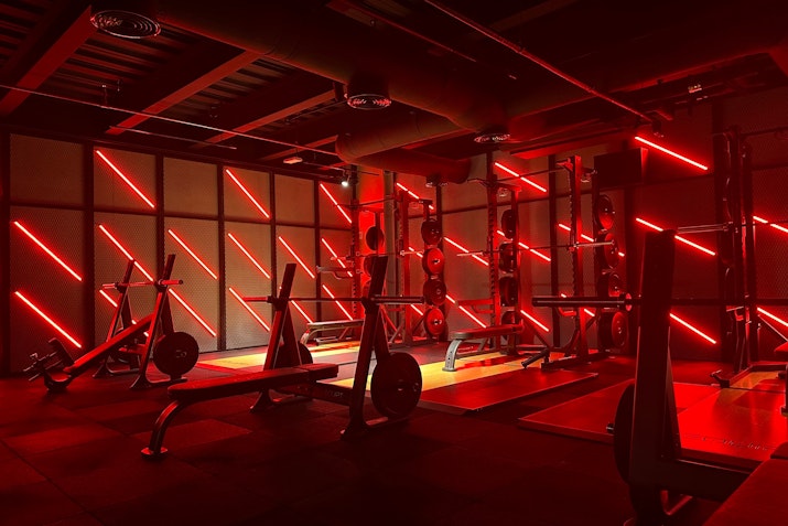 Gym with intense red lighting, highlighting the workout equipment and creating an energizing atmosphere.