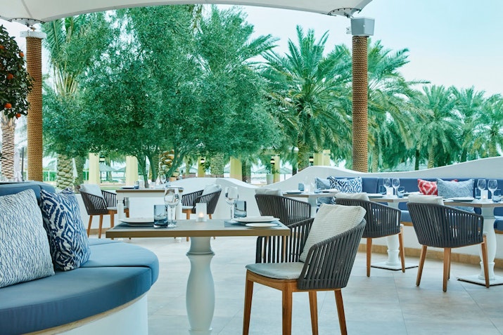 Outdoor dining area with comfortable seating, surrounded by palm trees and lush greenery.