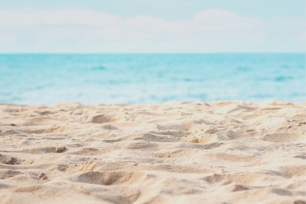 A sandy beach with the ocean in the background.