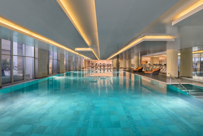 Indoor swimming pool with bright lighting and seating area.