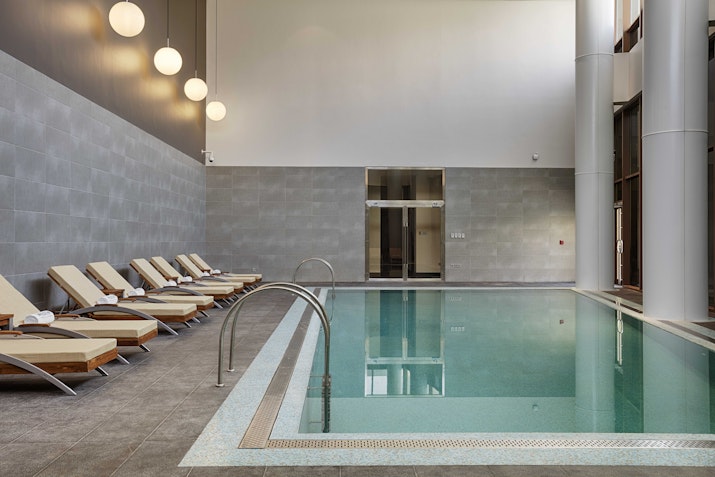 Indoor pool area with lounge chairs and soft lighting.