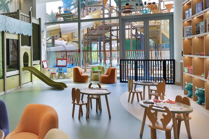 Fun For Mini Privilee’ers Children's playroom with colorful furniture and a slide in the background.