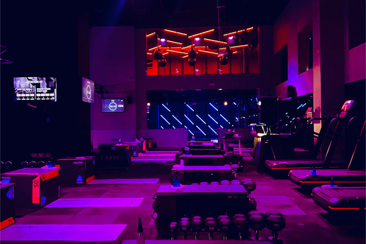 Fitness studio with neon lighting, workout equipment, and a high-tech atmosphere.