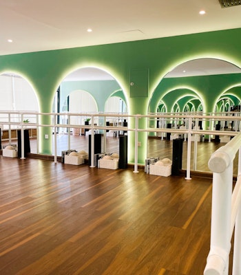 Ox Fitness Lab Modern dance studio with green arches, wooden flooring, and mirrored walls