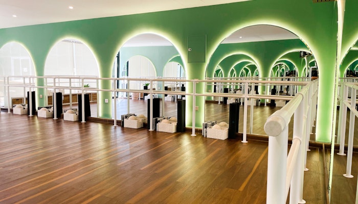 Ox Fitness Lab Modern dance studio with green arches, wooden flooring, and mirrored walls
