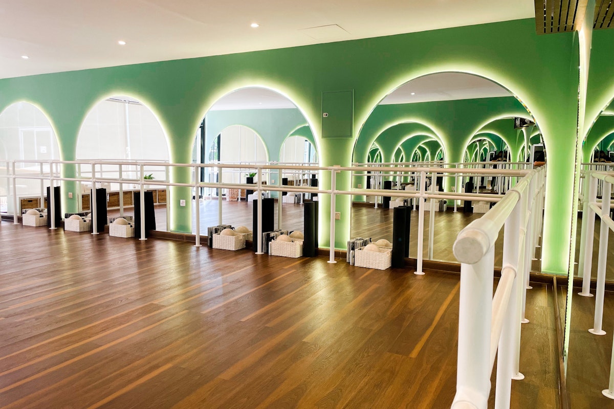 Ox Fitness Lab Modern dance studio with green arches, wooden flooring, and mirrored walls
