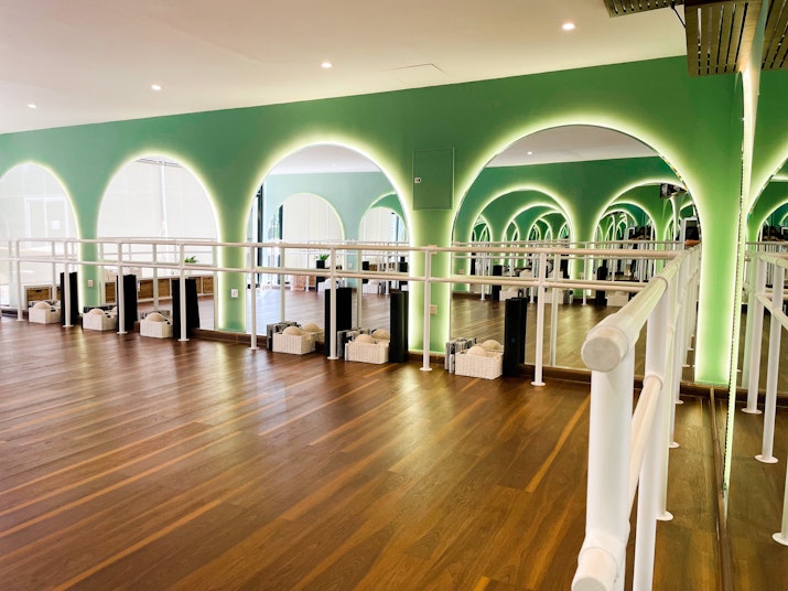 Modern dance studio with green arches, wooden flooring, and mirrored walls
