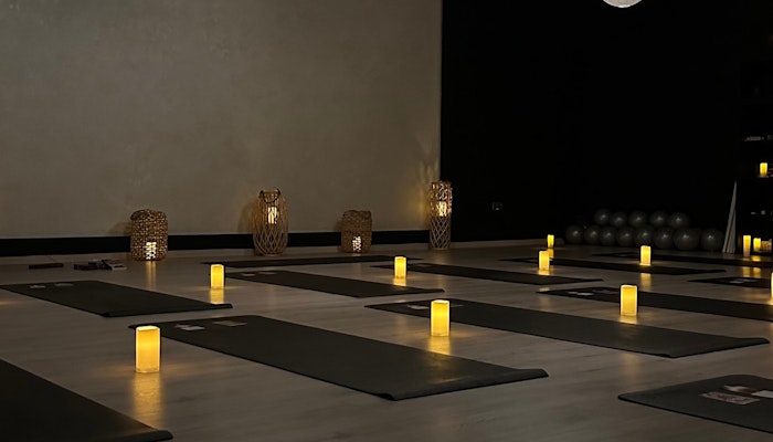 Yoga at SoulHIIT A peaceful yoga studio with dim lighting, soft candles placed on the floor near yoga mats, and decorative lamps creating a calm and serene atmosphere.
