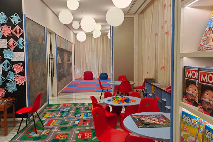 Colorful children's playroom with red chairs, toys, and a carpet, featuring bright pendant lights
