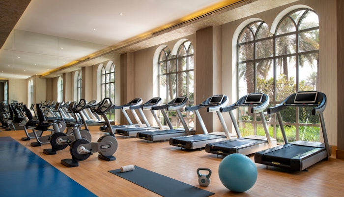 Marsa Malaz Kempinski Health Club Gym with exercise machines and equipment near large windows.