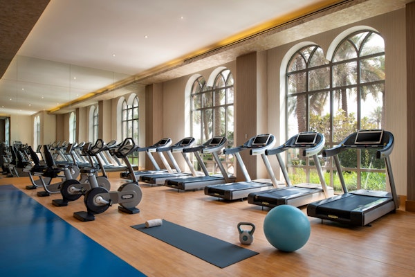 Gym with exercise machines and equipment near large windows.