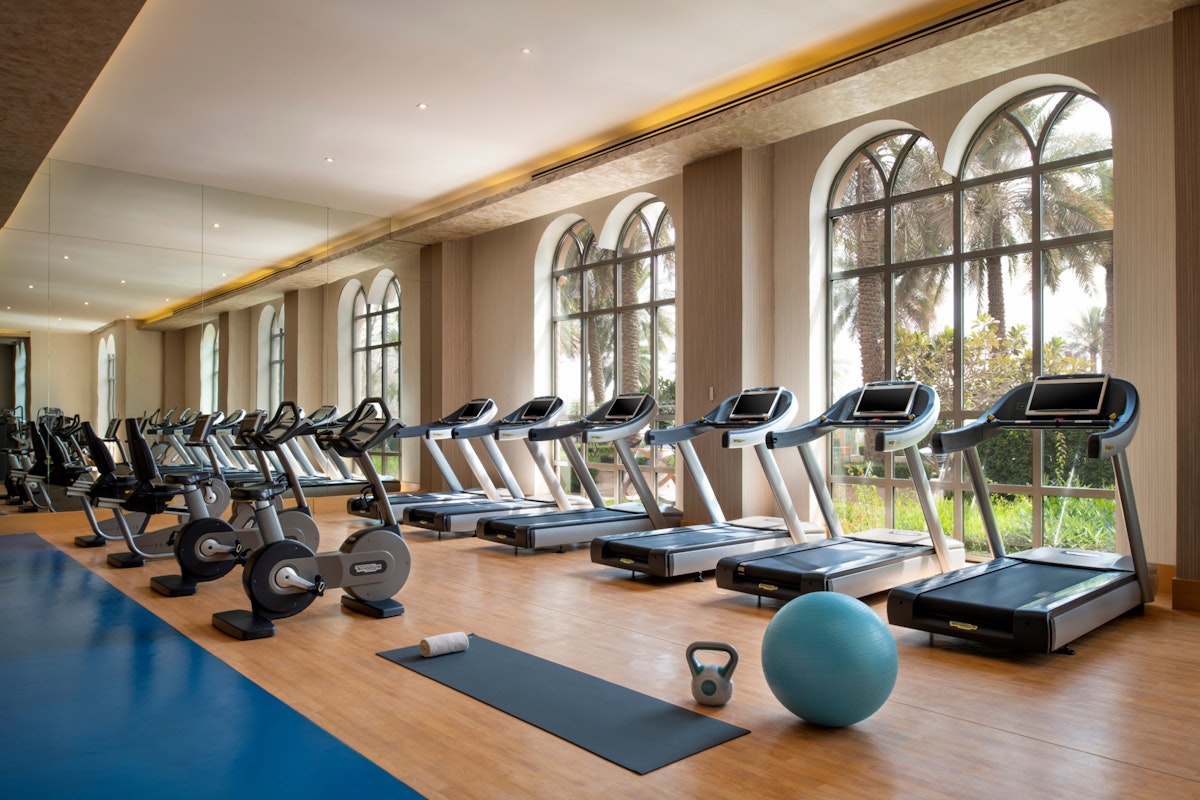 Gym with exercise machines and equipment near large windows.