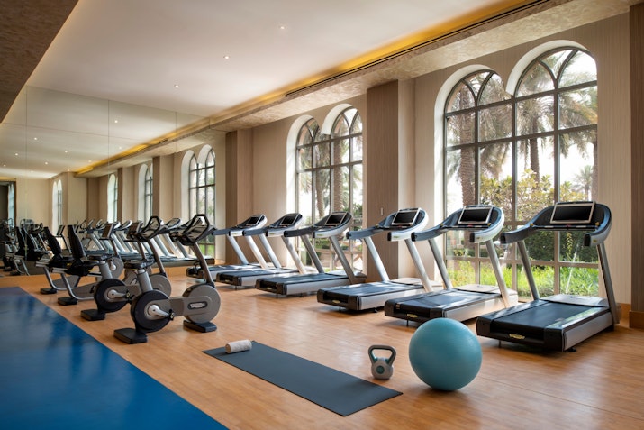 Gym with exercise machines and equipment near large windows.