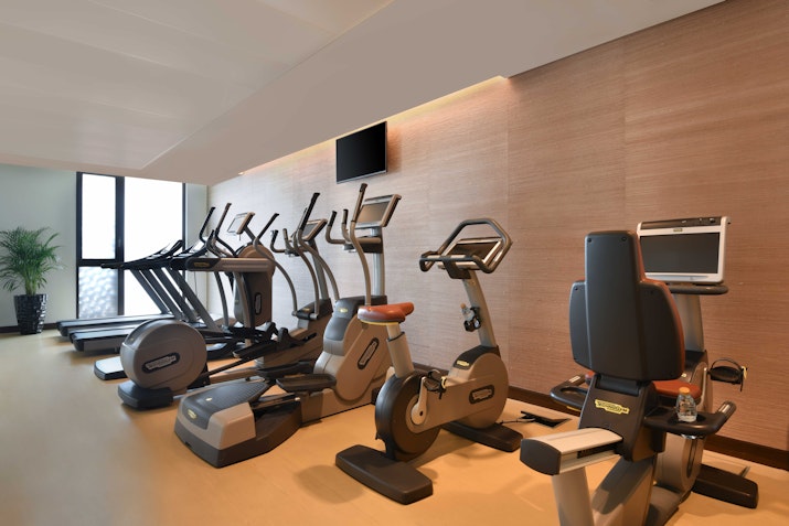Gym with ellipticals and exercise machines, with large windows letting in natural light