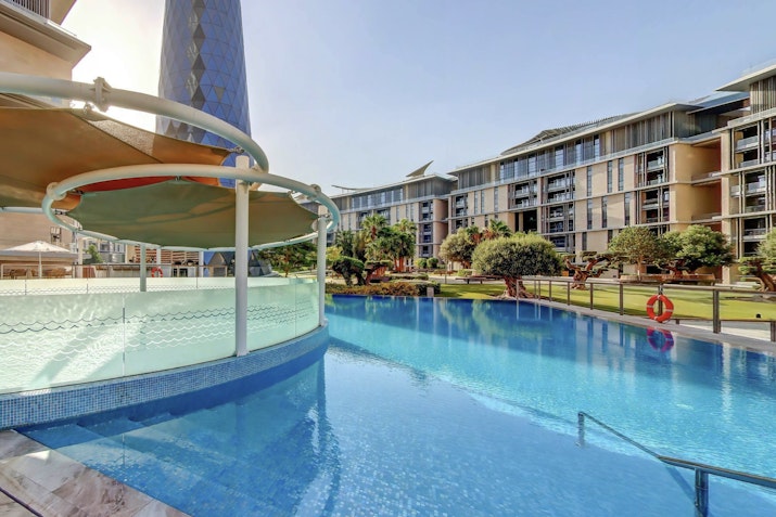 Swimming pool with a curved slide and residential buildings in the background.