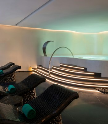 Banyan Tree Doha Luxurious spa room with curved lounge chairs, ambient lighting, and a circular Jacuzzi.