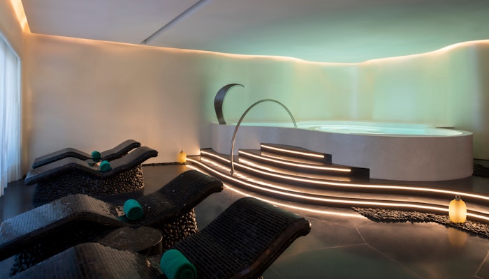 Banyan Tree Doha Luxurious spa room with curved lounge chairs, ambient lighting, and a circular Jacuzzi.
