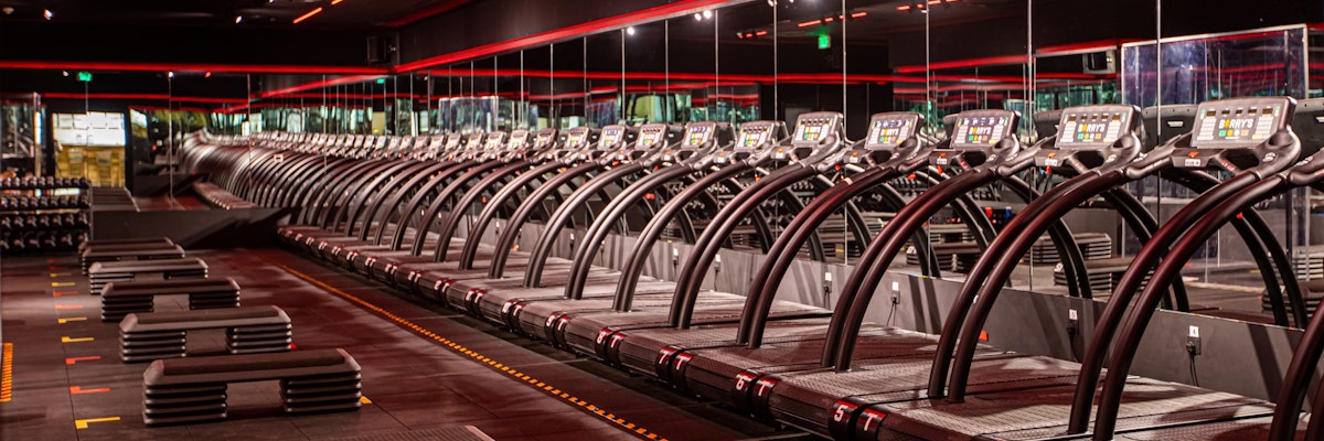 Barry's Doha Red Room Gym with rows of treadmills, exercise benches, and red ambient lighting