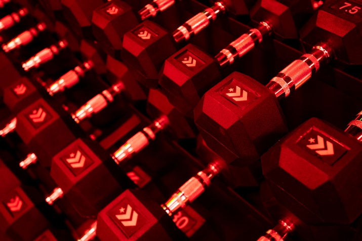 Close-up of dumbbells arranged neatly, illuminated with red lighting